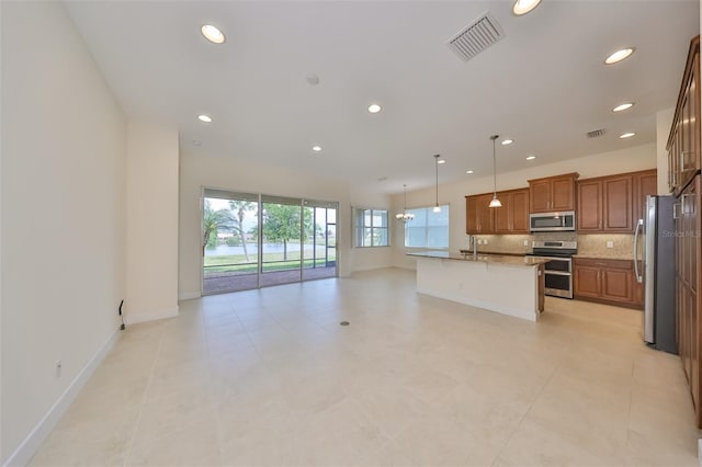 kitchen with decorative backsplash, appliances with stainless steel finishes, a breakfast bar, a kitchen island with sink, and decorative light fixtures