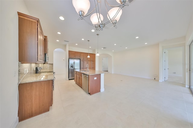 kitchen with stainless steel appliances, sink, a chandelier, hanging light fixtures, and an island with sink