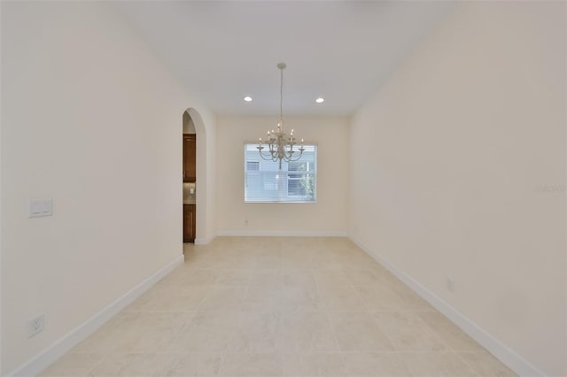 empty room with a notable chandelier and light tile patterned flooring