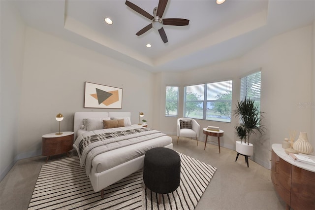 carpeted bedroom with a raised ceiling and ceiling fan