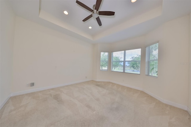 unfurnished room featuring ceiling fan, light carpet, and a tray ceiling