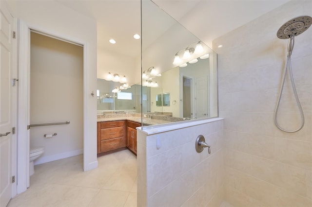 bathroom with a tile shower, tile patterned floors, vanity, and toilet