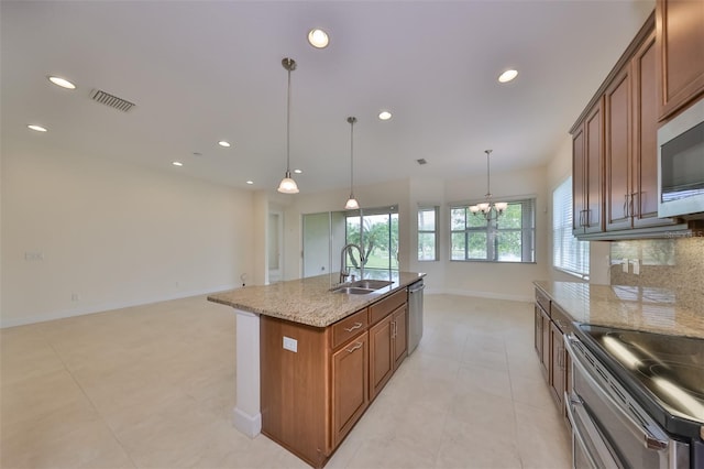 kitchen with stainless steel appliances, a kitchen island with sink, sink, and hanging light fixtures