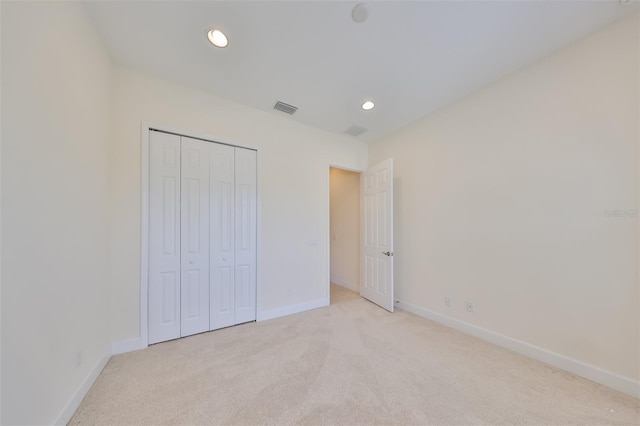 unfurnished bedroom with light carpet and a closet