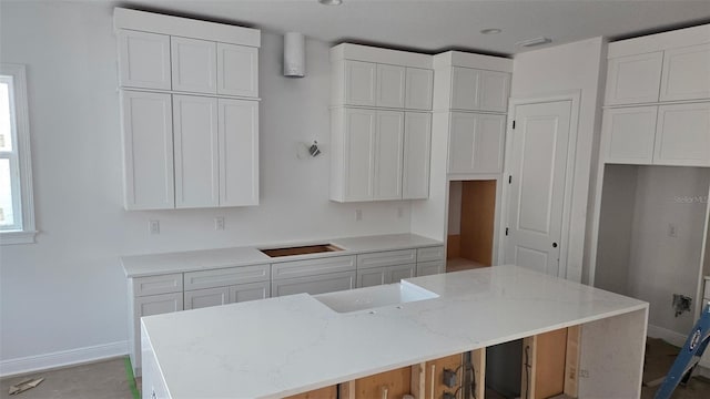 kitchen with light stone countertops, white cabinets, and a kitchen island