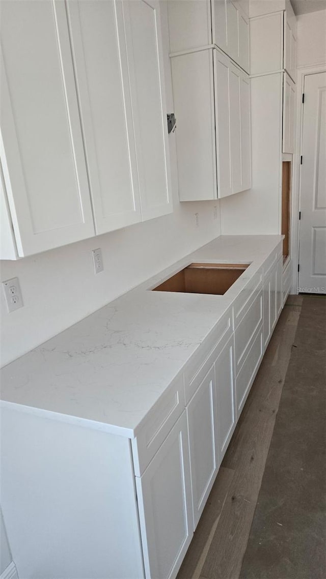 kitchen featuring light stone countertops, dark wood-type flooring, white cabinets, and black electric cooktop