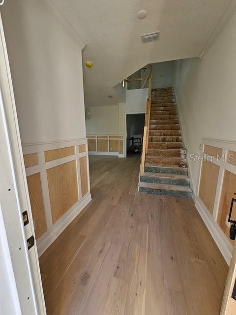 stairs with a wainscoted wall, visible vents, a decorative wall, and wood finished floors