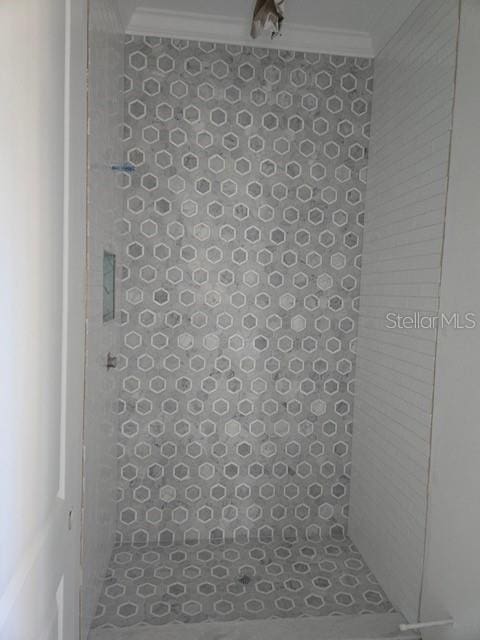 full bath with ornamental molding and tiled shower