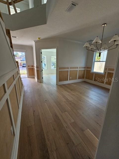 empty room featuring a chandelier, wood finished floors, and visible vents