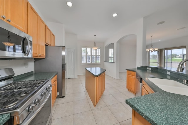 kitchen with stainless steel appliances, a chandelier, light tile floors, and a kitchen island