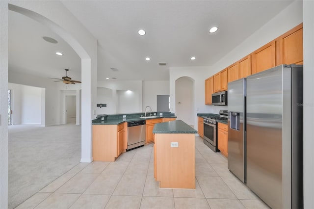 kitchen featuring a kitchen island, appliances with stainless steel finishes, sink, ceiling fan, and light colored carpet