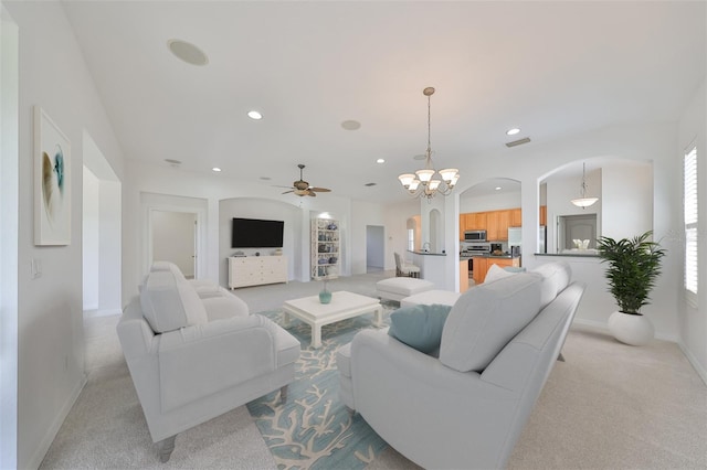 carpeted living room with ceiling fan with notable chandelier