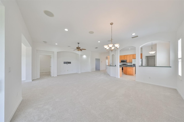 unfurnished living room with ceiling fan with notable chandelier and light carpet