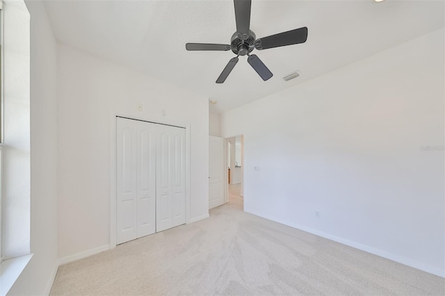 unfurnished bedroom featuring a closet, ceiling fan, and light colored carpet