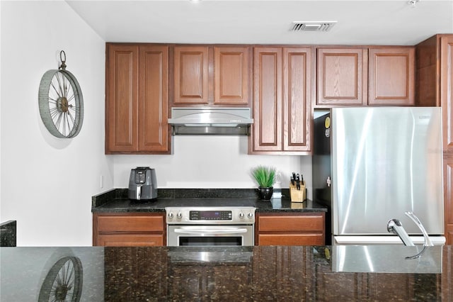 kitchen with sink, dark stone counters, stainless steel fridge, and range