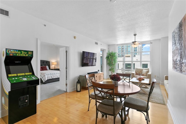 dining room featuring ceiling fan, light hardwood / wood-style floors, and a textured ceiling