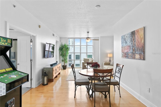 dining space with ceiling fan, expansive windows, light hardwood / wood-style flooring, and a textured ceiling