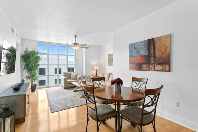 dining space with floor to ceiling windows, ceiling fan, light hardwood / wood-style floors, and a textured ceiling