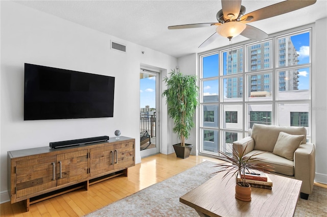 living room featuring a wealth of natural light, ceiling fan, and light wood-type flooring