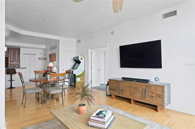 living room with ceiling fan and light hardwood / wood-style flooring