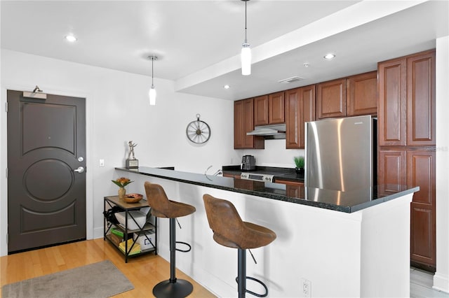 kitchen with light hardwood / wood-style flooring, hanging light fixtures, electric range oven, a kitchen bar, and stainless steel refrigerator