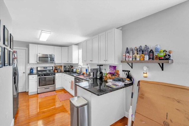 kitchen featuring white cabinets, stainless steel appliances, kitchen peninsula, and light hardwood / wood-style flooring