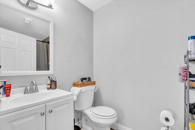 bathroom with curtained shower, vanity, and toilet