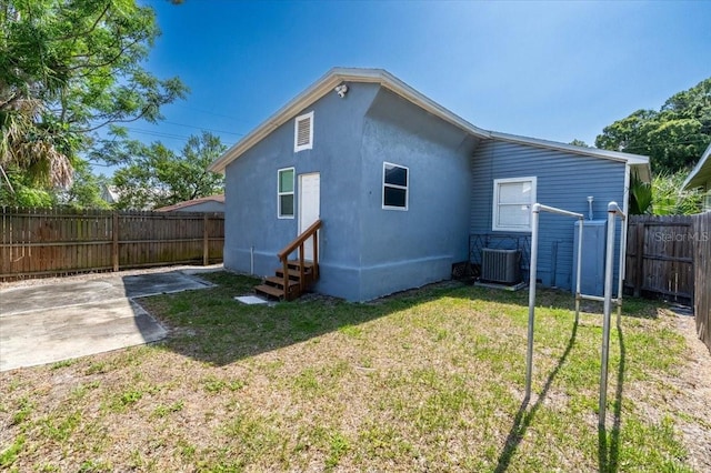 rear view of house featuring central AC unit, a yard, and a patio