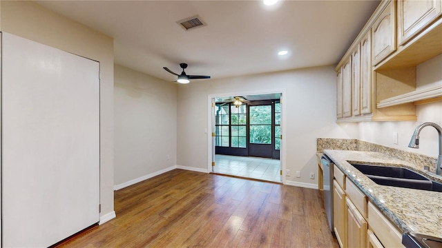 kitchen featuring ceiling fan, light stone counters, hardwood / wood-style flooring, and sink