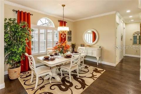 dining area with dark wood-type flooring, crown molding, and a healthy amount of sunlight