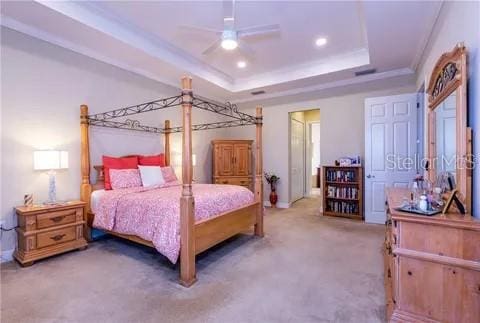 carpeted bedroom featuring a raised ceiling and crown molding