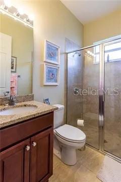 bathroom with toilet, vanity, and a shower with door