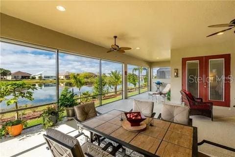 sunroom / solarium with ceiling fan, french doors, a water view, and a wealth of natural light