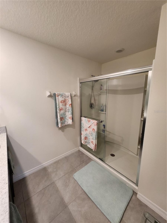 bathroom featuring tile patterned flooring, vanity, an enclosed shower, and a textured ceiling