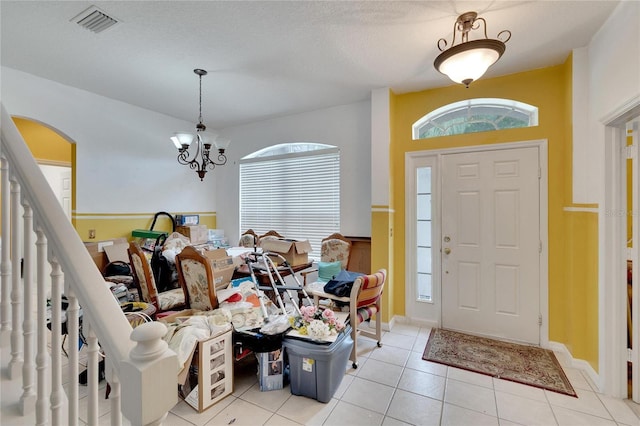 entryway featuring an inviting chandelier, a textured ceiling, and light tile floors