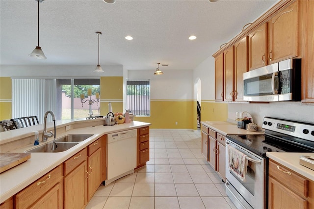 kitchen featuring hanging light fixtures, a textured ceiling, appliances with stainless steel finishes, sink, and light tile floors