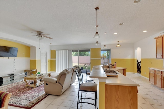 kitchen with decorative light fixtures, sink, light tile flooring, and a kitchen island