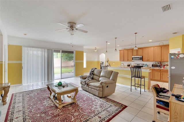 living room with sink, ceiling fan, and light tile floors