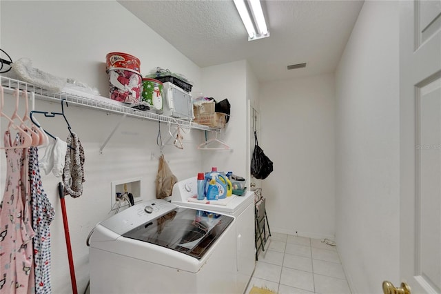 laundry room with washer hookup, a textured ceiling, light tile floors, and washing machine and dryer