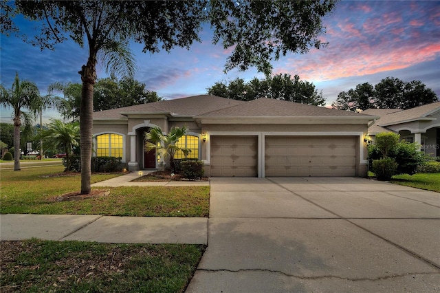 ranch-style home featuring a garage and a lawn