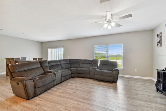 living room with plenty of natural light, ceiling fan, and light hardwood / wood-style flooring