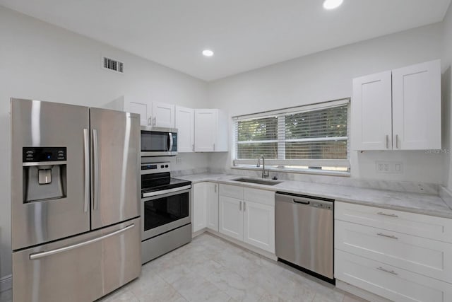 kitchen with white cabinetry, appliances with stainless steel finishes, sink, and light tile floors