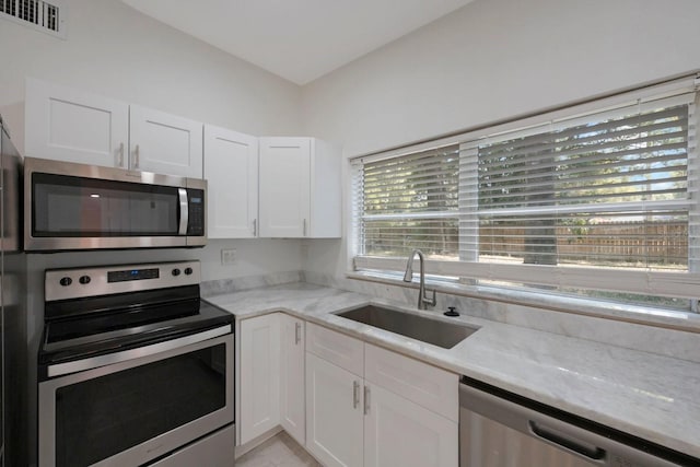 kitchen with light stone countertops, sink, white cabinets, and appliances with stainless steel finishes