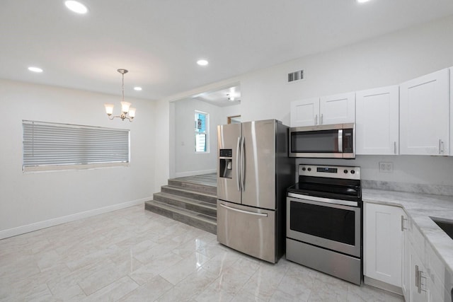 kitchen with white cabinetry, an inviting chandelier, appliances with stainless steel finishes, decorative light fixtures, and light tile floors