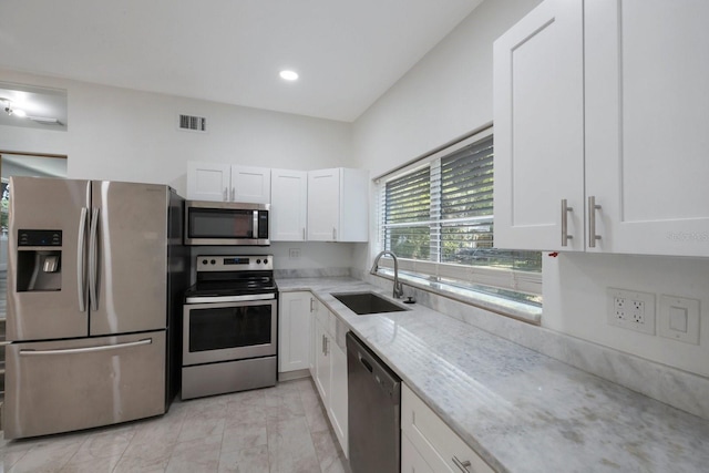 kitchen featuring light tile flooring, light stone countertops, white cabinets, sink, and appliances with stainless steel finishes