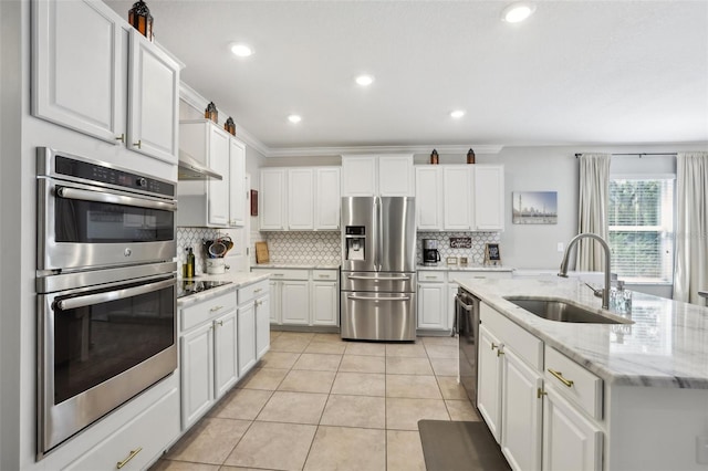 kitchen with tasteful backsplash, stainless steel appliances, sink, a kitchen island with sink, and white cabinetry