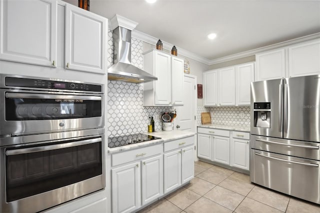 kitchen featuring crown molding, stainless steel appliances, white cabinets, wall chimney exhaust hood, and backsplash