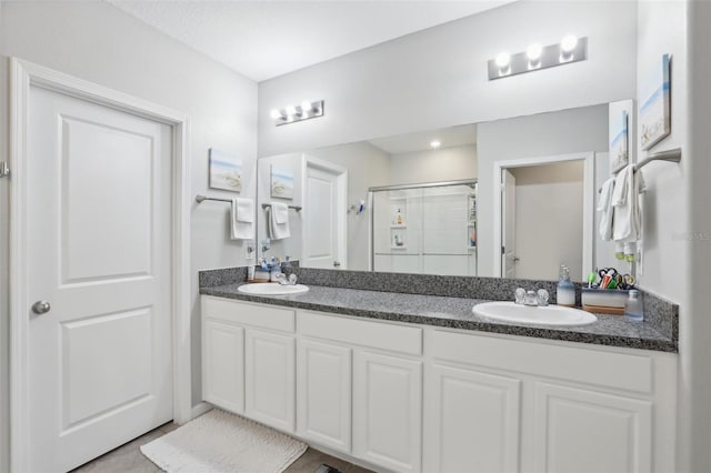 bathroom featuring vanity with extensive cabinet space, walk in shower, and dual sinks