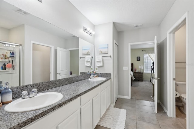 bathroom featuring dual vanity, a textured ceiling, toilet, and tile floors