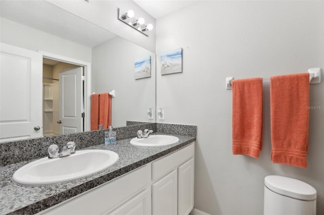 bathroom with dual sinks, vanity with extensive cabinet space, and toilet